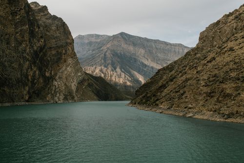 Free A tranquil lake nestled between towering rocky mountains under a cloudy sky, offering a sense of peace and isolation. Stock Photo