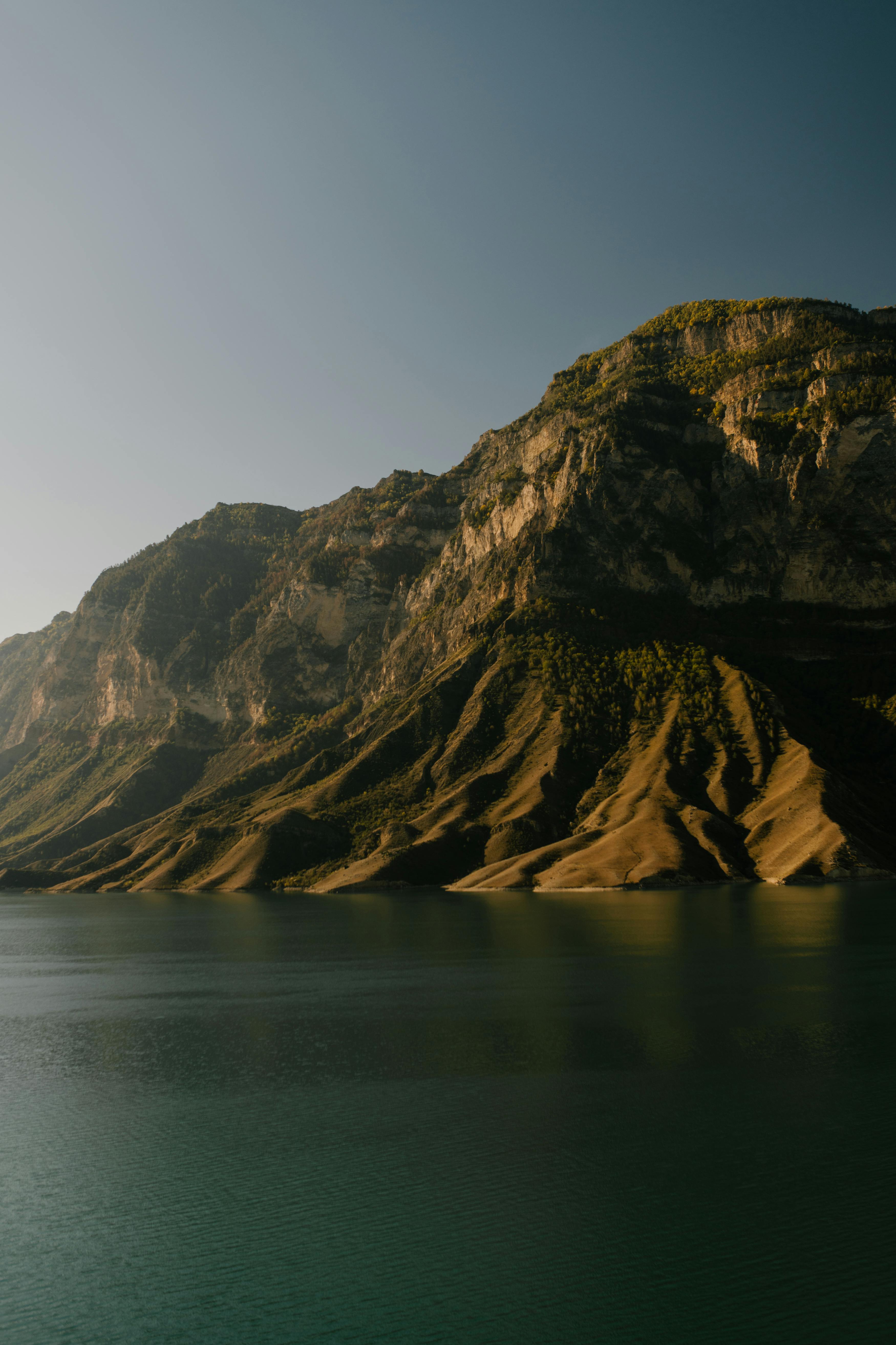 晴朗的天空下，高耸的山脉倒映在宁静的水面上，令人叹为观止
