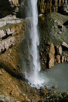 Captivating vertical waterfall cascading over rocky cliffs into a serene pool.