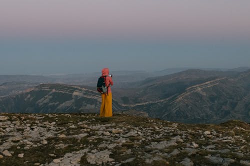 Woman with Backpack Standing on Hilltop