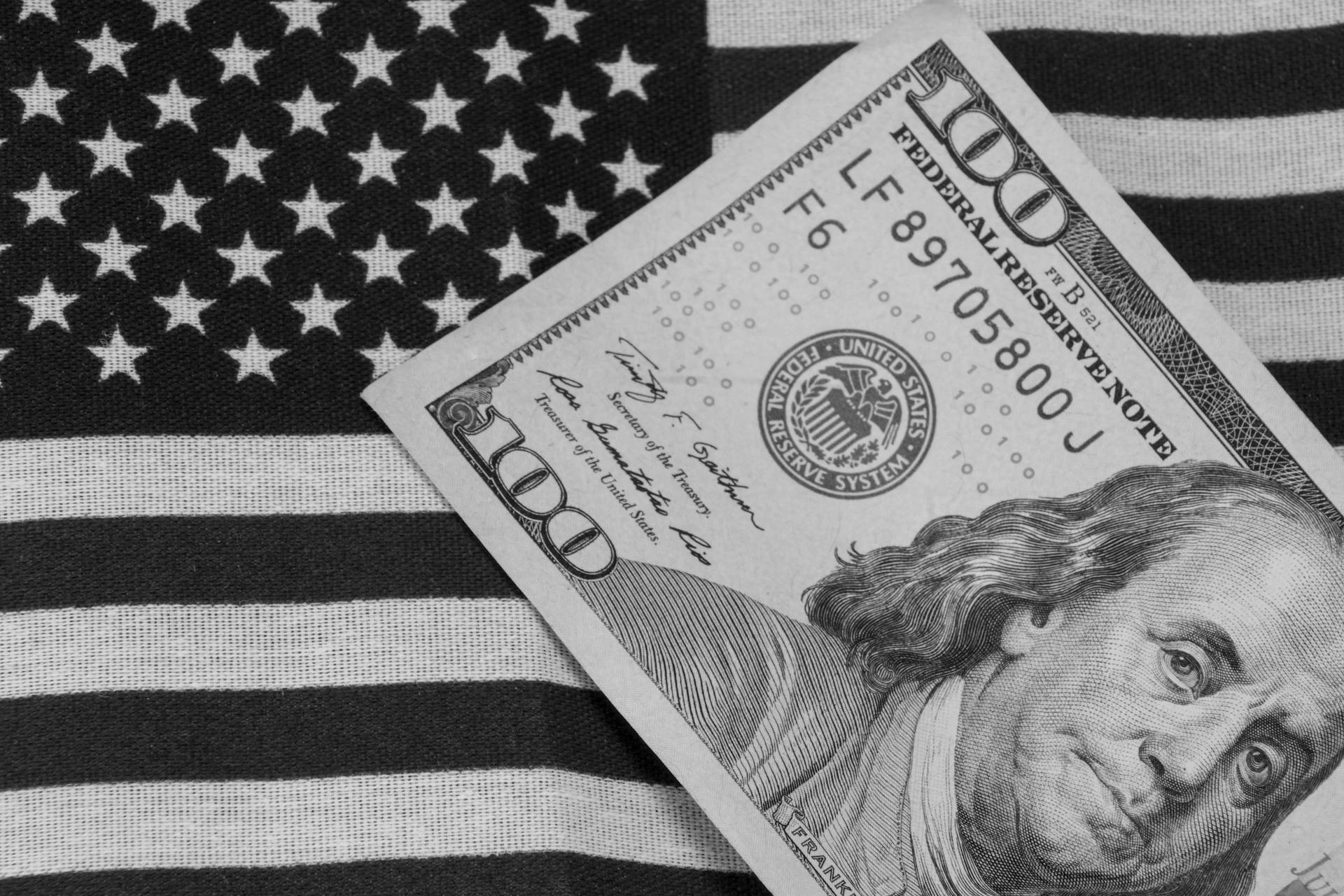 Grayscale image of US dollar bill on American flag for symbolic financial concept.