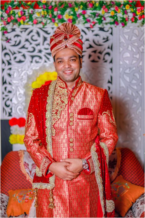 Free An Indian groom wearing a traditional red sherwani and turban at a vibrant wedding ceremony. Stock Photo
