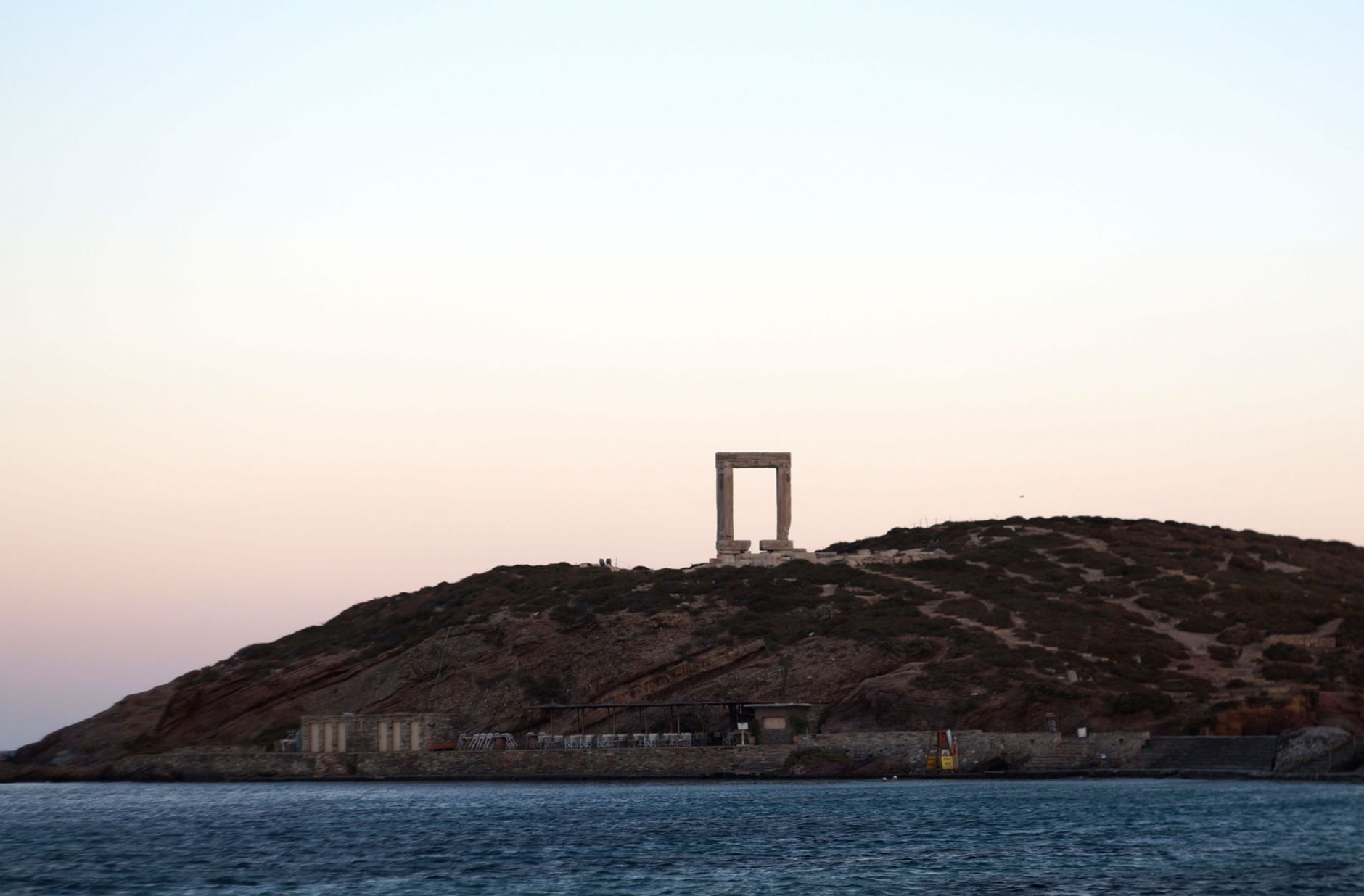Ancient marble gate of Portara at sunset in Naxos