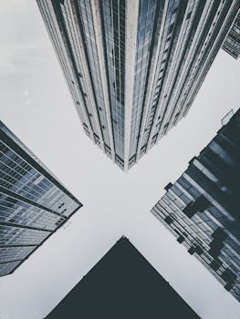 Intersecting skyscraper silhouettes form an X against the sky in this urban architecture shot.