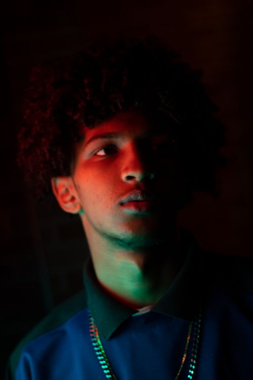 Free Moody portrait of a young man with afro hairstyle under dramatic lighting. Stock Photo