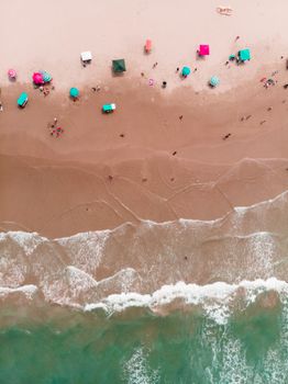 Drone capture of Ciudad Madero beach with colorful umbrellas and clear waves.