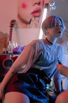 Young woman in edgy attire with neon lights and fashion elements.
