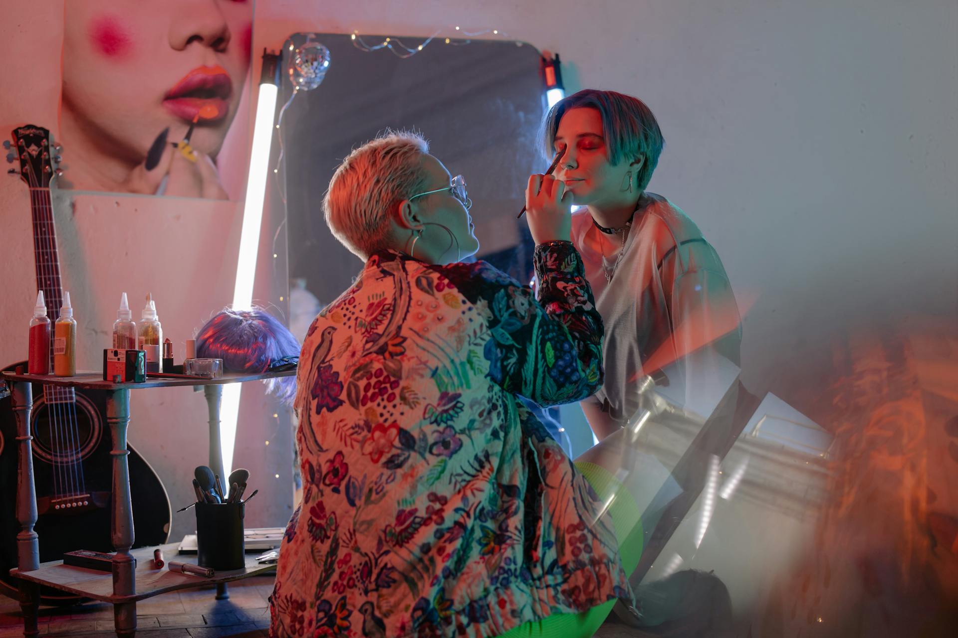 Vibrant studio portrait of makeup artist applying cosmetics to a model's face.