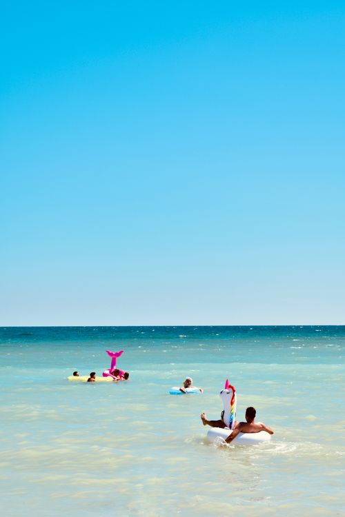 Free Group of people floating on inflatable toys at a sunny tropical beach. Stock Photo