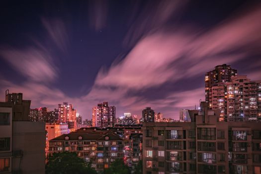 Vivid cityscape at night with illuminated skyscrapers and dynamic cloud formations.