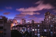 夜幕下，灯火璀璨的城市景观与紫色天空交相辉映，展现出摩天大楼的现代风貌