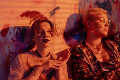 Free Two stylish women with bold makeup pose in an artistic room, creating a unique fashion portrait. Stock Photo