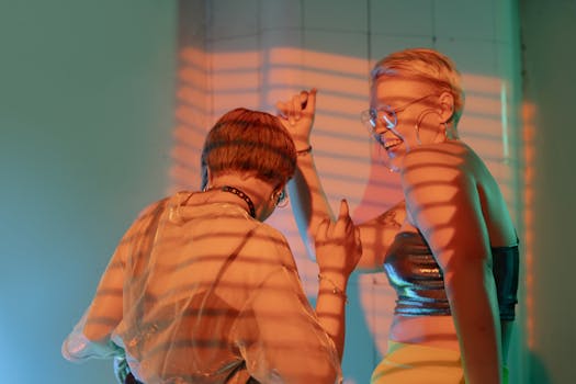 两个女人在室内随着多彩灯光跳舞，沉浸在活力四射的派对氛围中