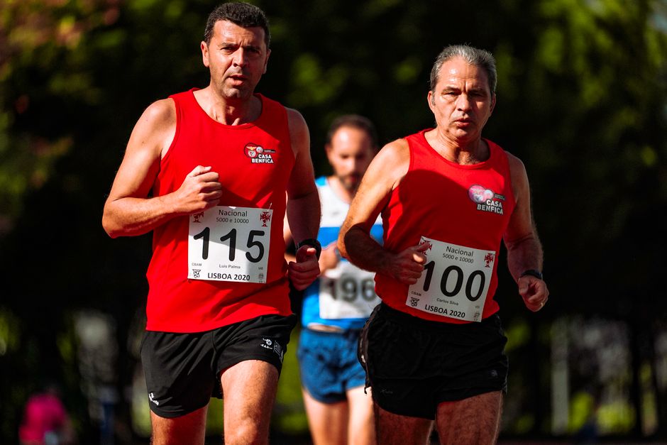 Focused mature male runners in active wear competing while participating in marathon in summer