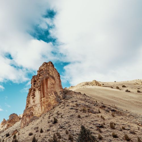 Free From below of dry top of hill with rocky formations located in steppe under cloudy sky in daytime Stock Photo