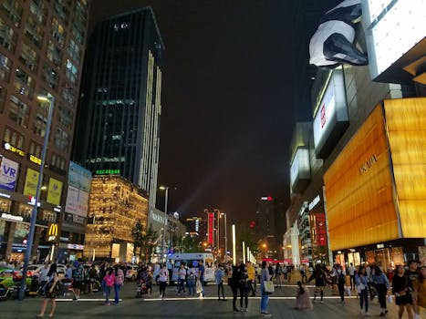 Bustling urban scene in Chengdu's shopping district with vibrant lights and crowds at night.