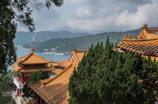 Golden-roofed Wen Wu Temple amidst lush green trees with Sun Moon Lake in the background. by Asian Wanderlust