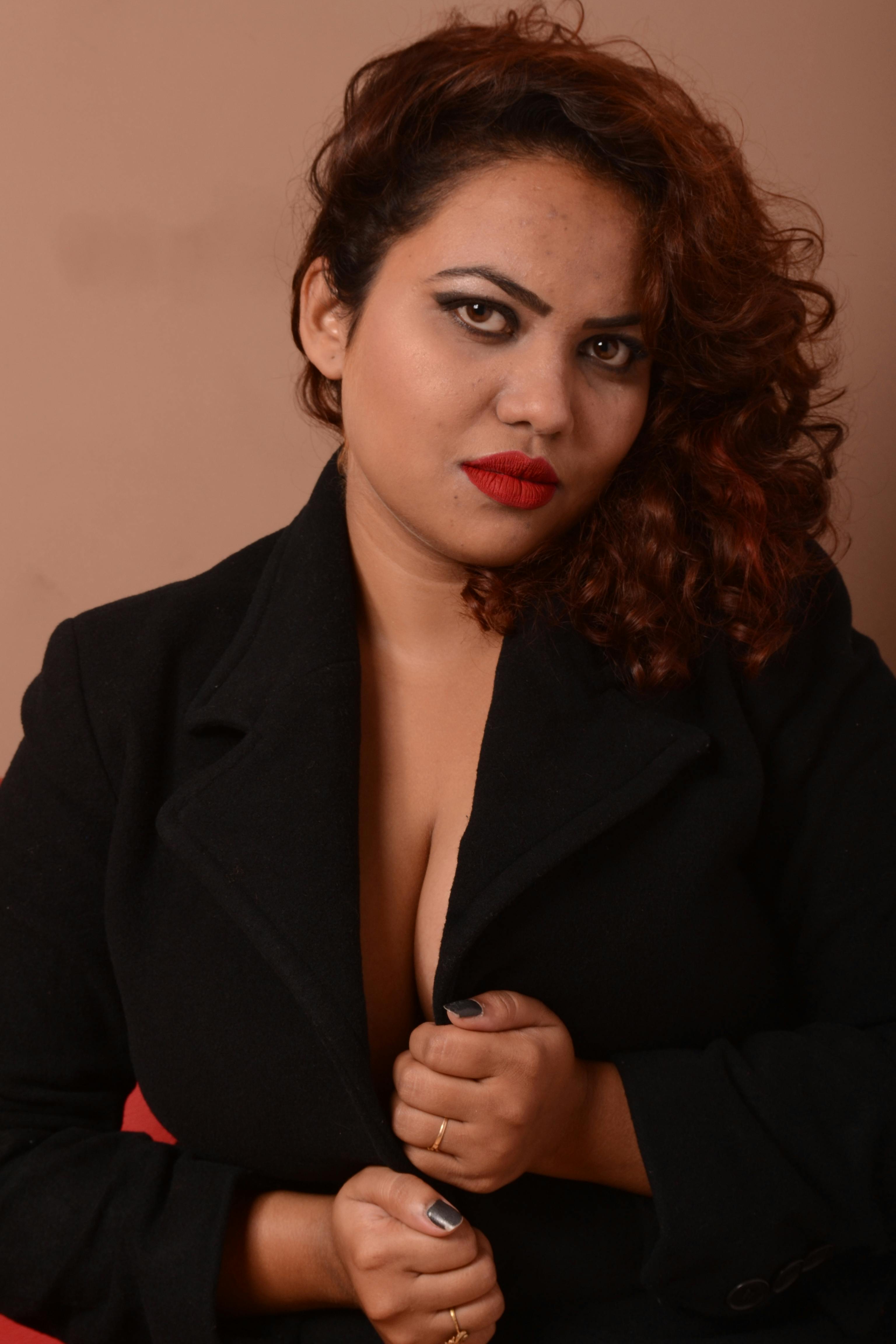 Confident woman in a black suit poses with a serious expression, showcasing elegance and style.