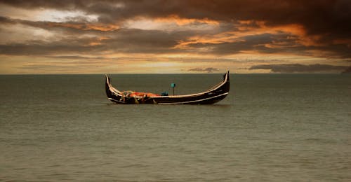 Black Boat on Sea during Sunset