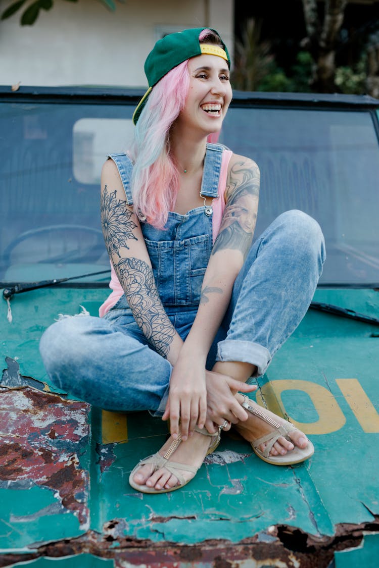 Joyful Woman With Pink Hair Sitting On Shabby Car Hood