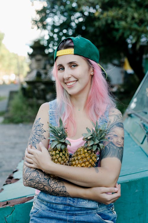 Woman with Arm Tattoos Holding Pineapples