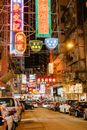 五颜六色的霓虹灯照亮了繁华的香港街道，停放的汽车和热闹的气氛相映成趣