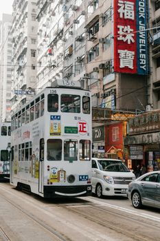 双层电车在香港繁忙的街道上行驶，周围是熙熙攘攘的车辆和充满活力的标志