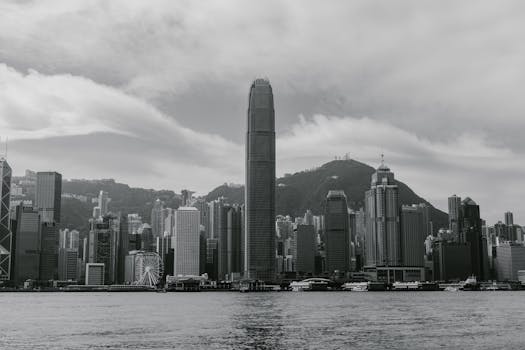 Black and white photograph of Hong Kong's skyline featuring modern skyscrapers and the sea.