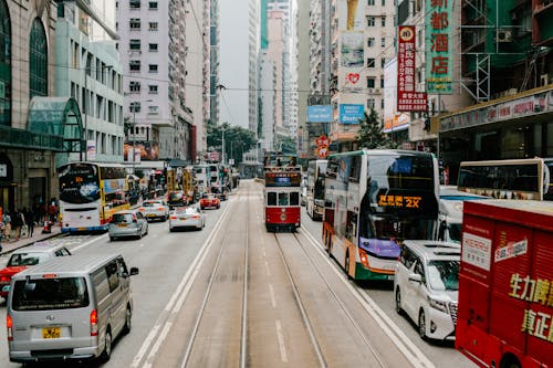 Tram, Buses and Vehicles on a Street Between Buildings