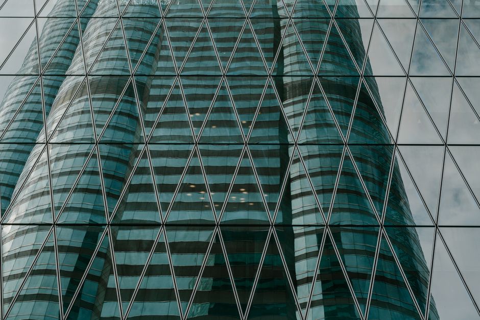 Reflection of modern skyscraper in glass façade, showcasing urban architecture