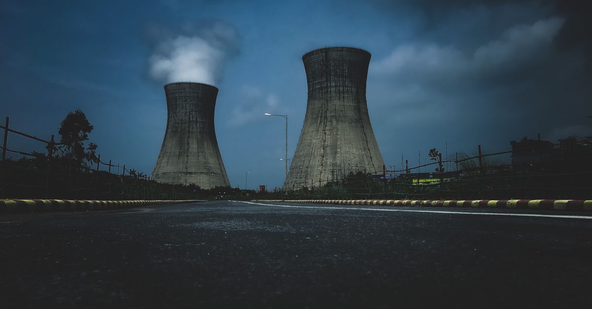 Moody view of industrial cooling towers with smoke against a twilight sky, emphasizing industry impact.