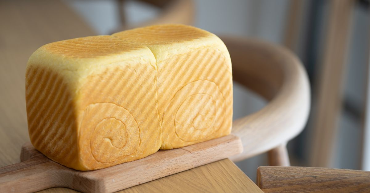 Close-up of a freshly baked artisan bread loaf on a wooden board, showcasing texture and detail.