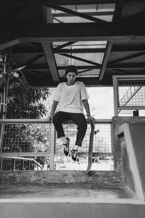 Free A young man sits in a skate park holding his skateboard. Black and white photo. Stock Photo
