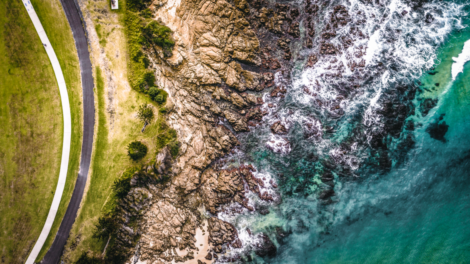Nitmiluk Scenic Express Helicopter Tour Fly Over 3 Gorges - A stunning aerial shot of the rocky shore at Narooma, NSW, with crashing waves and a winding coastal path.