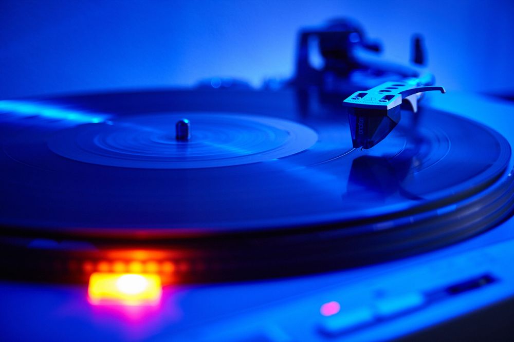 Vinyl record spinning under colorful music lighting