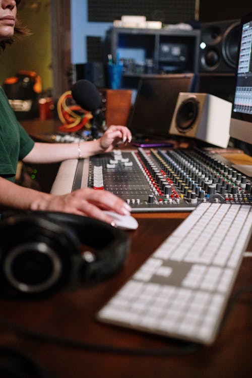 A Person in Green Crew Neck T-shirt Holding Computer Mouse Infront of Audio Mixer