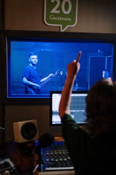 Musician playing guitar in a soundproof studio with sound engineer directing.