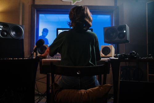 Free A music producer works in a sound studio with microphones and speakers, creating audio content. Stock Photo
