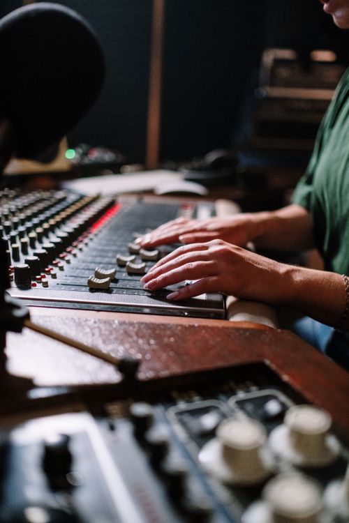 Free Close-up of hands adjusting sound mixer in a music studio setting. Stock Photo
