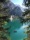 People Riding a Wooden Boat on Green Lake Near Mountains