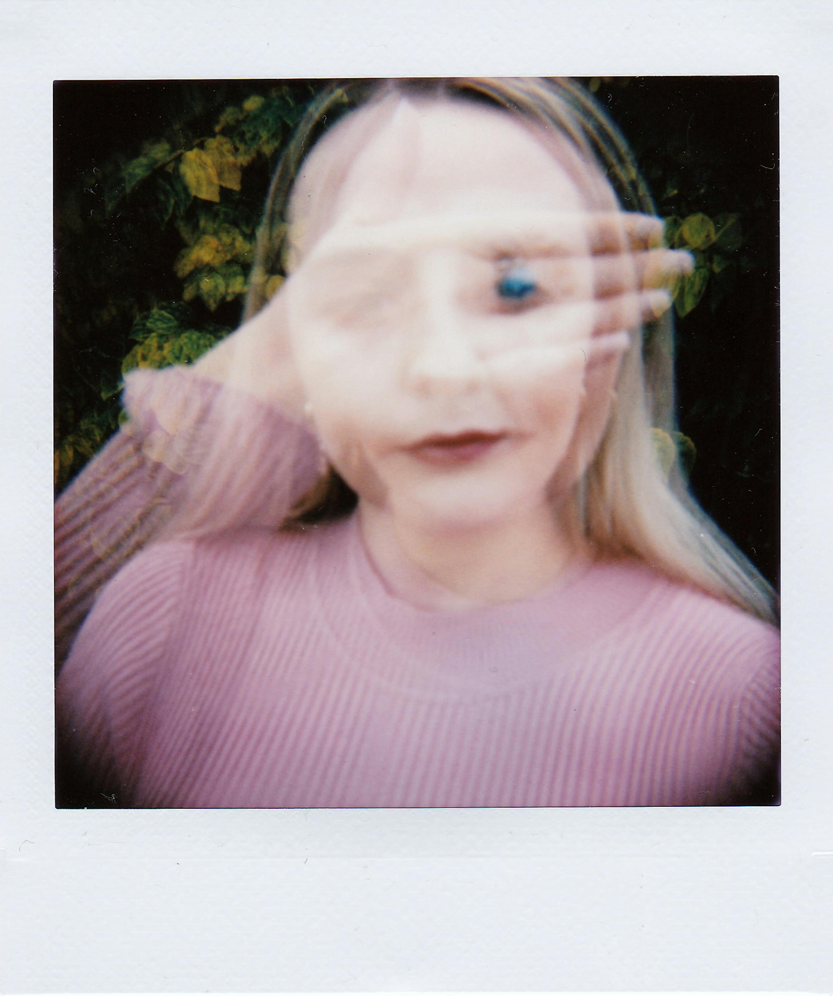 一张女人的双重曝光肖像，用模糊的手遮住脸，营造出艺术效果