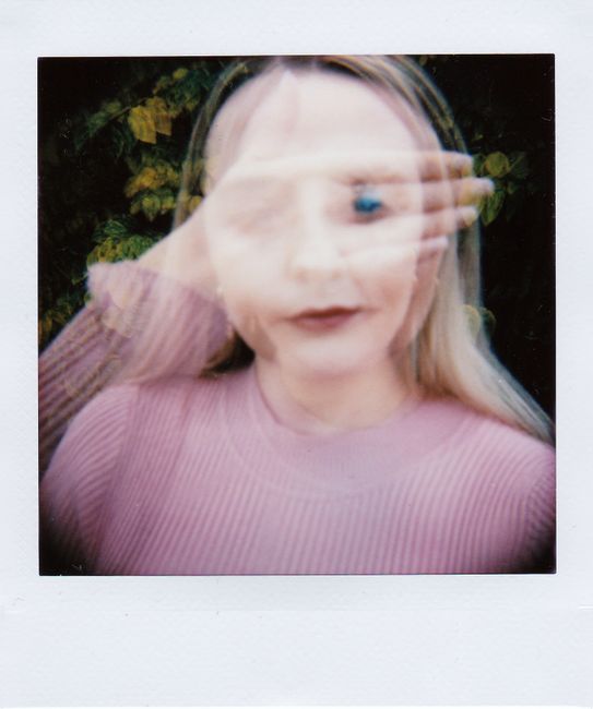 Double exposure portrait of a woman with a blurred hand covering her face, creating an artistic effect.
