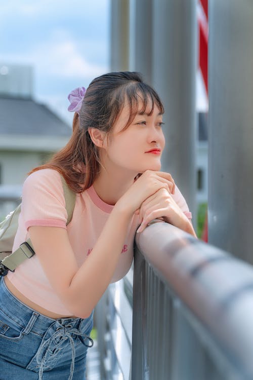 Free Woman in Pink Shirt Leaning on a Railing Stock Photo