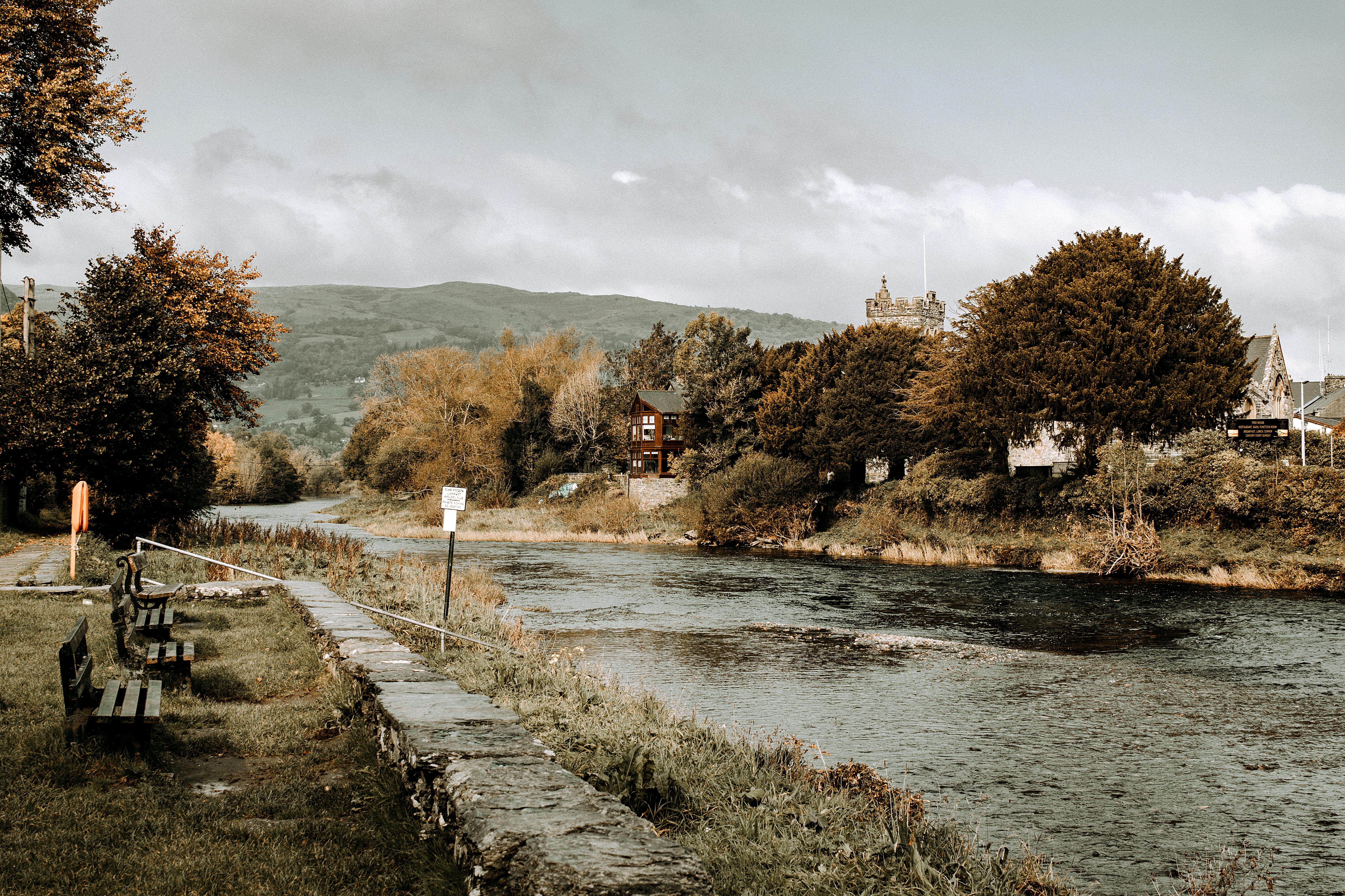Serene riverside landscape in Llanrwst, Wales, featuring benches and natural scenery.