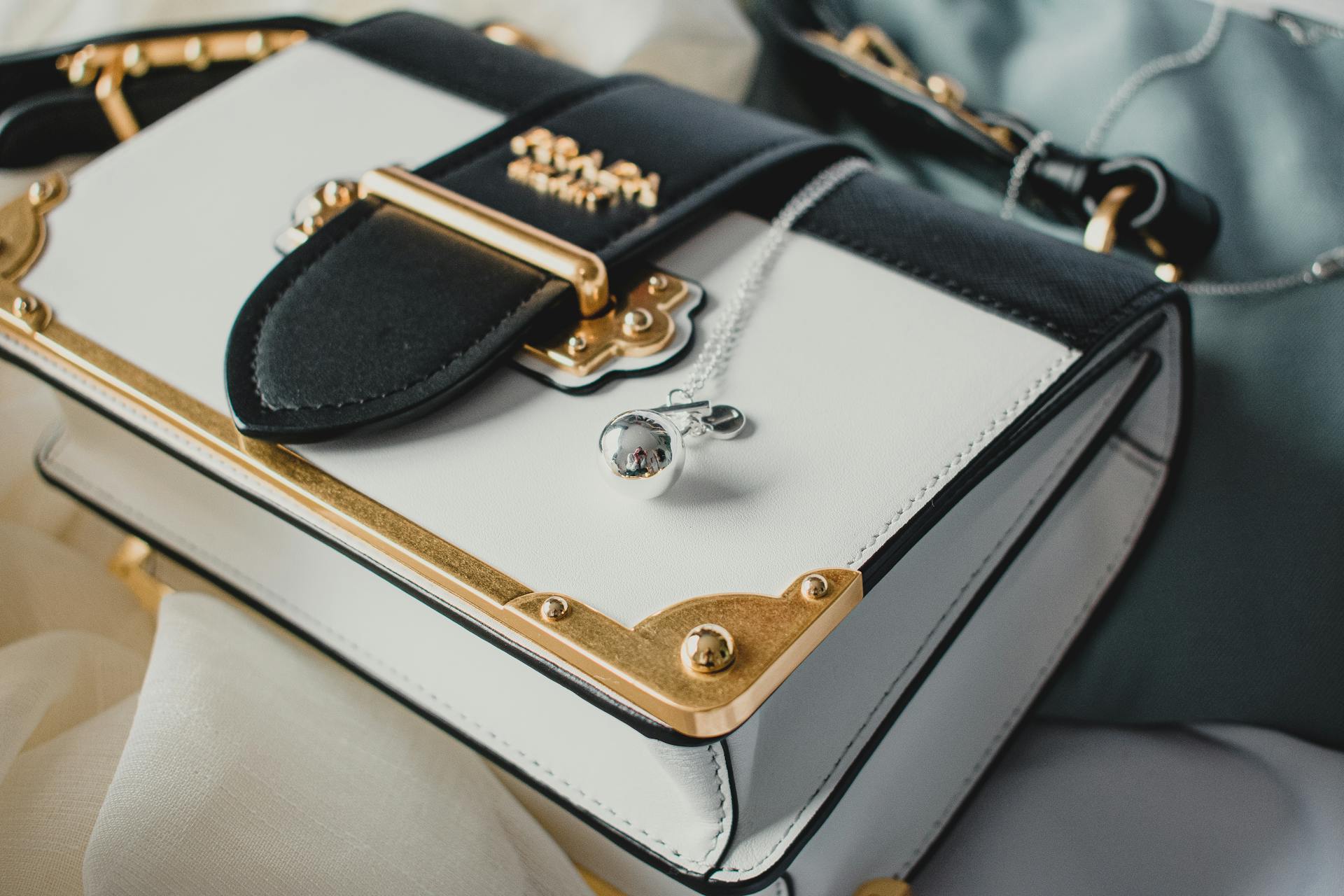 Close-up of a luxurious designer handbag with gold accents and a silver chain detail.