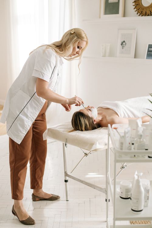 Free A relaxing facial treatment in a bright, professional spa environment featuring a dermatologist and client. Stock Photo