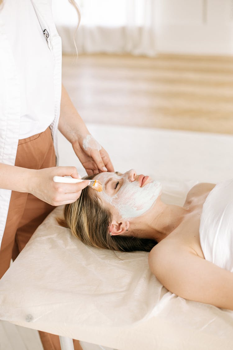 A Woman Lying On Bed Having A Facial Treatment