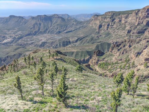 Free A breathtaking aerial view of the rugged mountain ranges in Gran Canaria, covered with lush green trees. Stock Photo