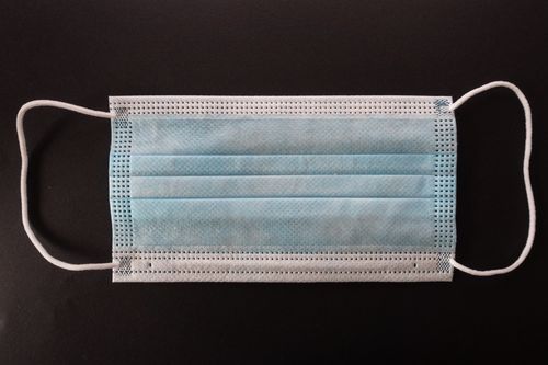 Free Close-up of a blue surgical face mask on a dark background for protection and prevention. Stock Photo