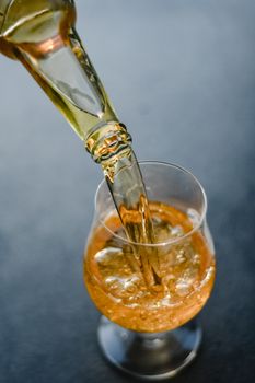 高角度镜头下，金色饮料被倒入玻璃杯，展示了其闪闪发光的质感